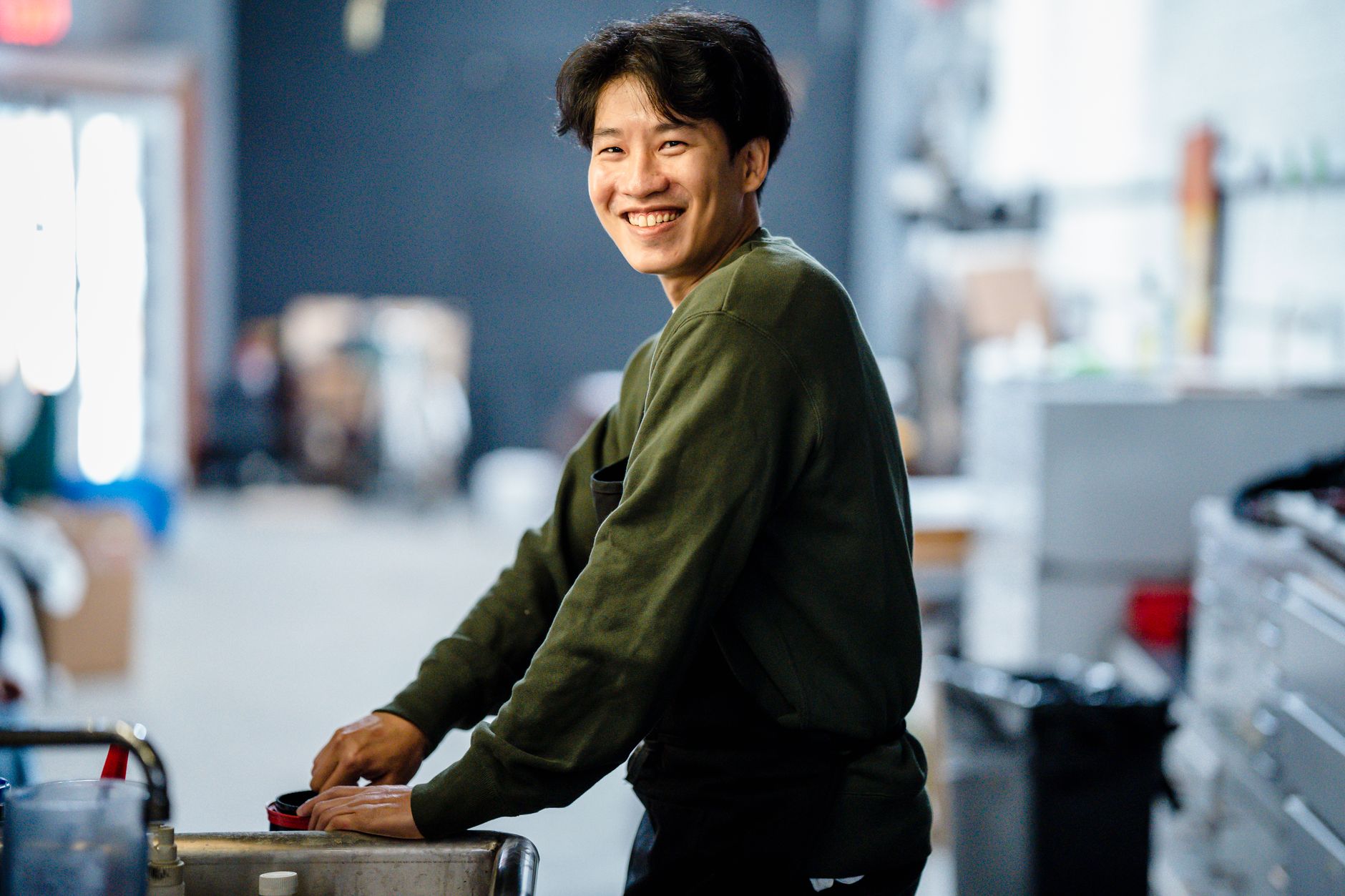 Portrait of a smiling man in a casual indoor workshop setting.