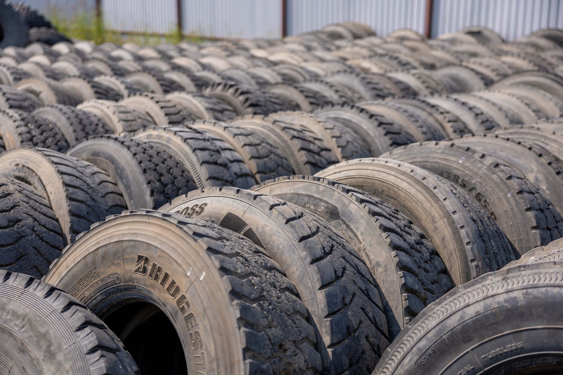A detailed view of numerous stacked used tires in an outdoor industrial environment.