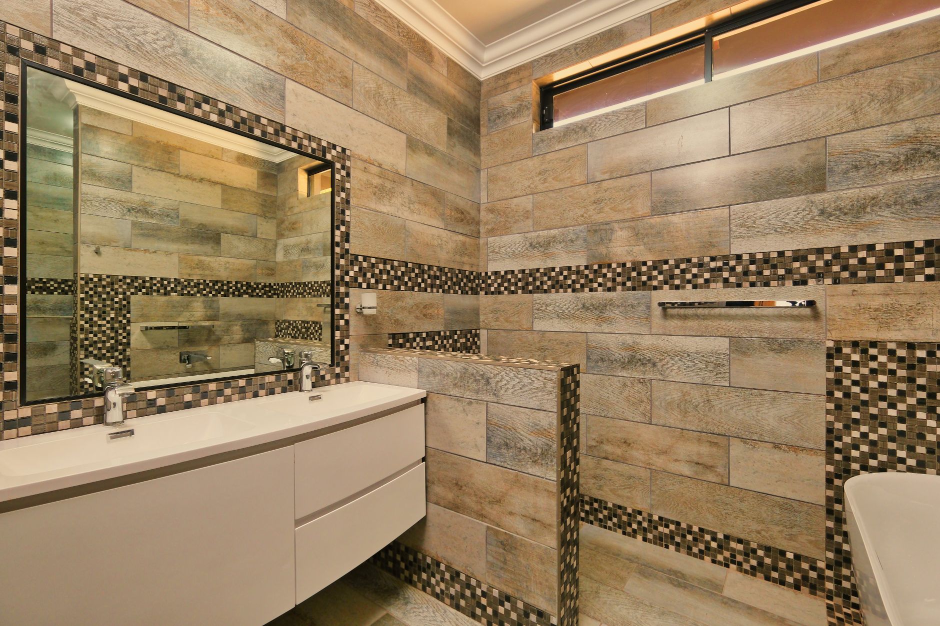 Elegant bathroom featuring mosaic tiles, large mirror, and minimalist sink design.
